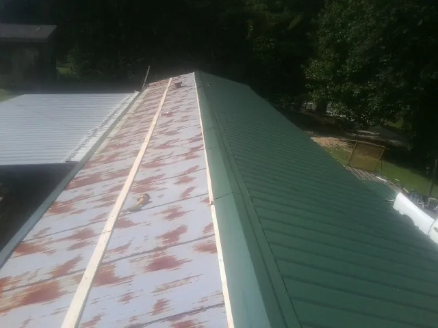 Old rusted panels beside newly installed green metal roofing — Wind Damage Roof Repair by Roofing Brothers in Berkeley
