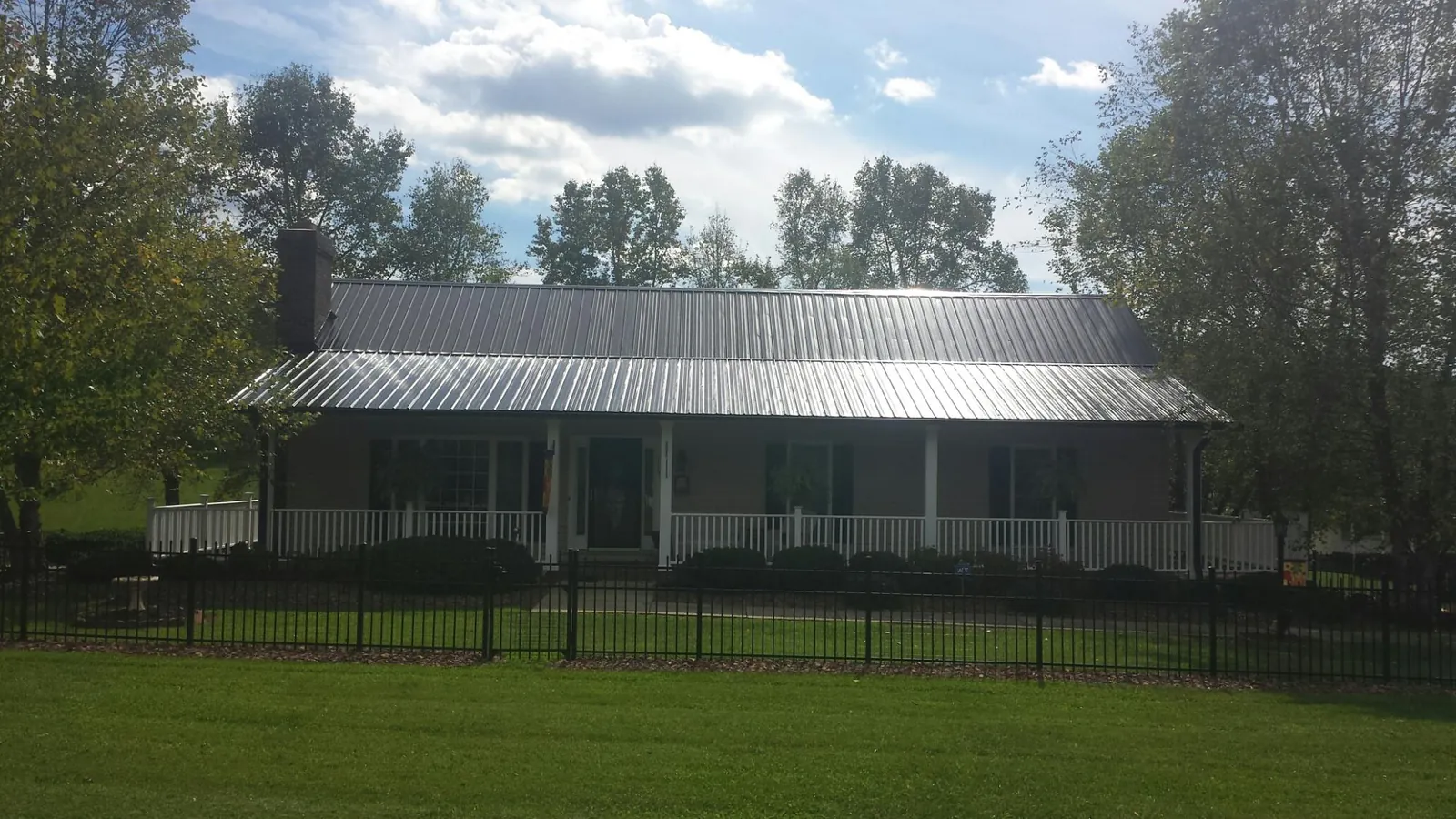 Gray metal roof on a brick ranch with a full width front porch — Gutter Guard Installation work by our crew in Berkeley